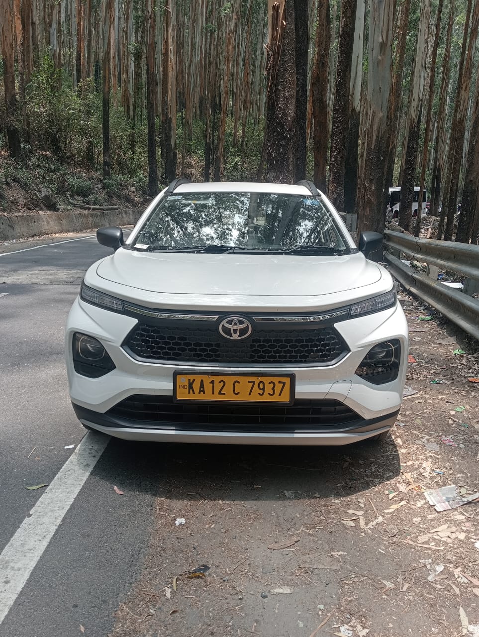 White SUV taxi front view on a forest road in Coorg